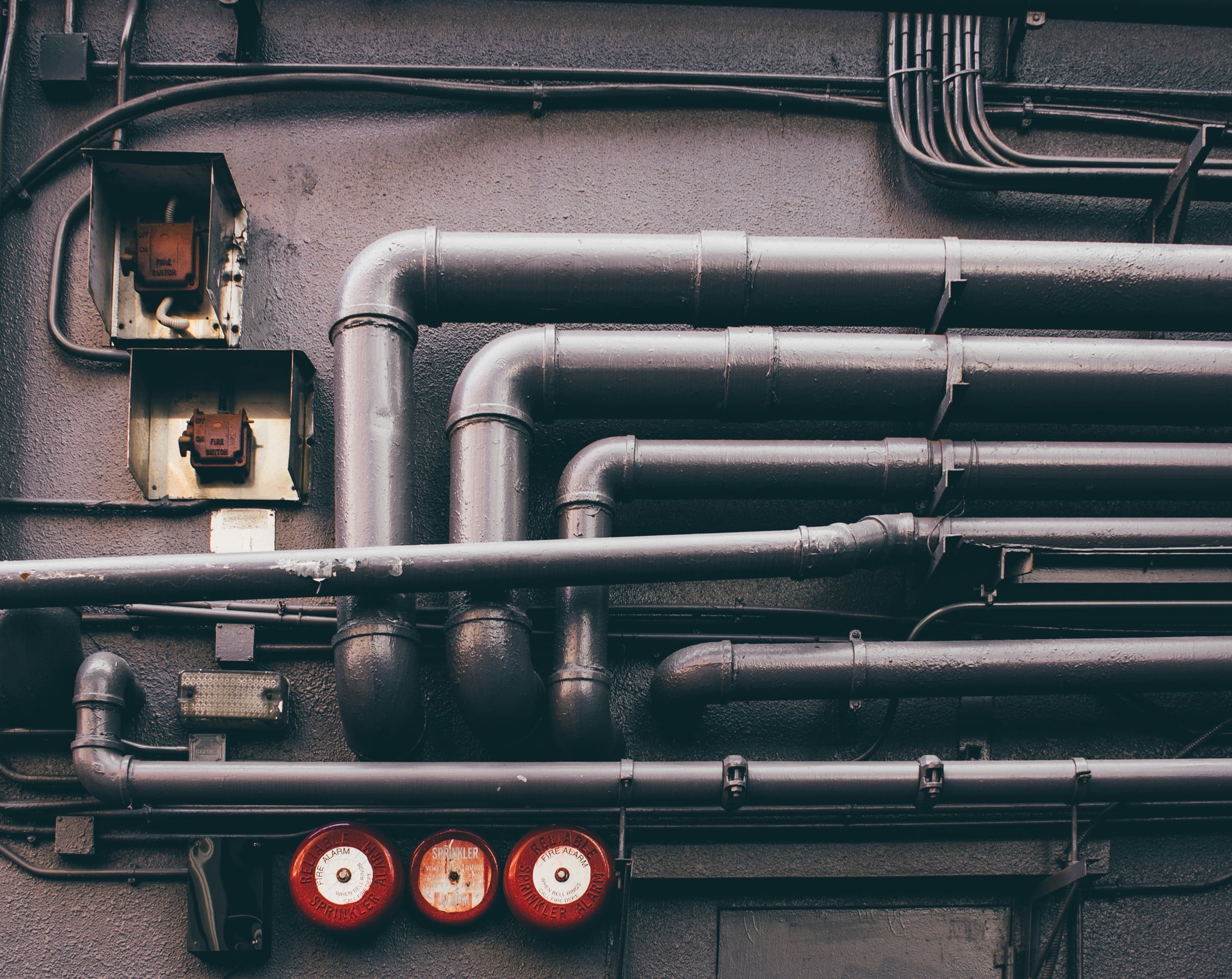 Industrial pipework with a section of damaged coating flagged for a ground-level check before anyone enters