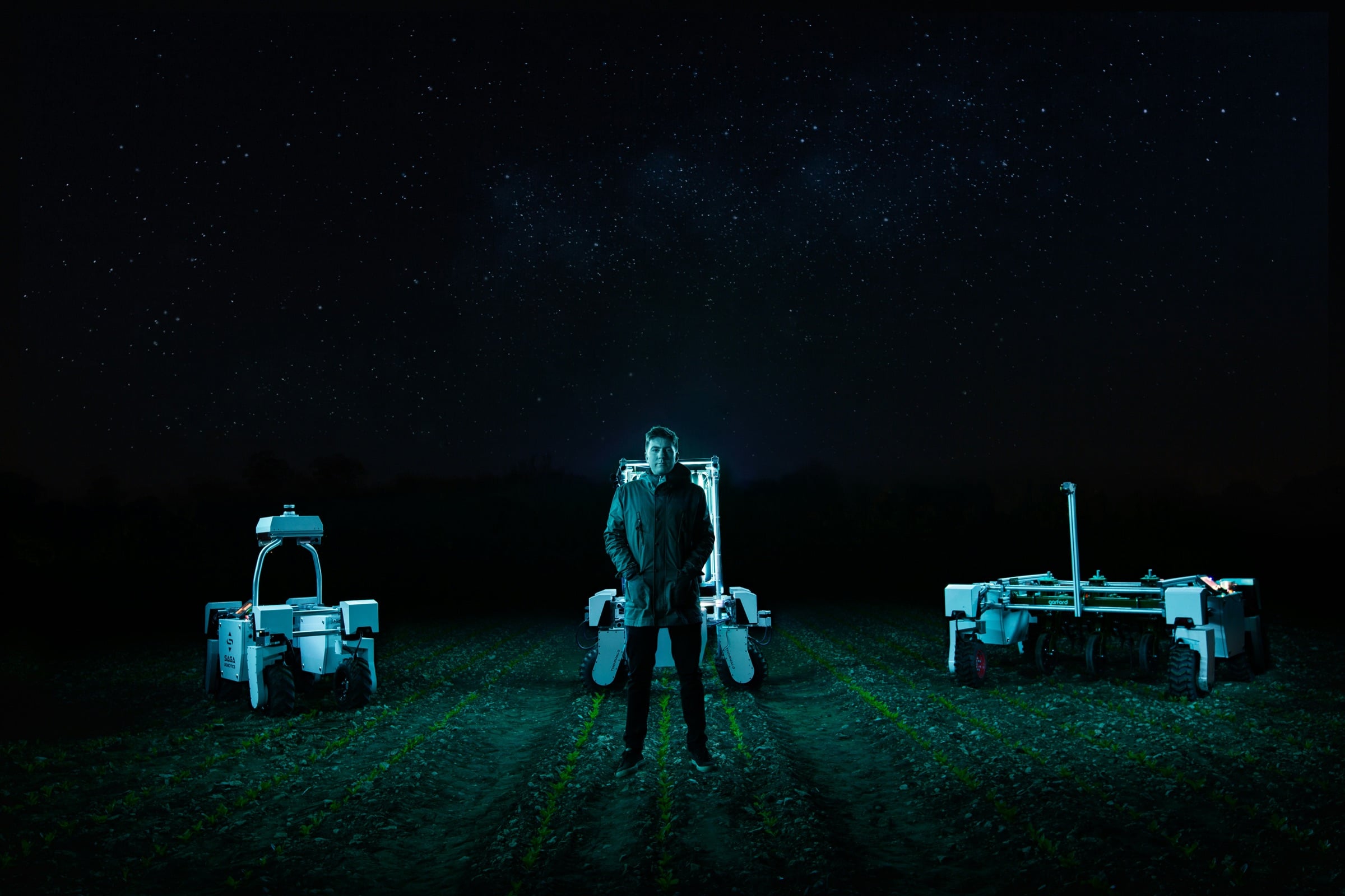 Three unmanned ground vehicles in a field at night with their operator, marked with each vehicle's task status
